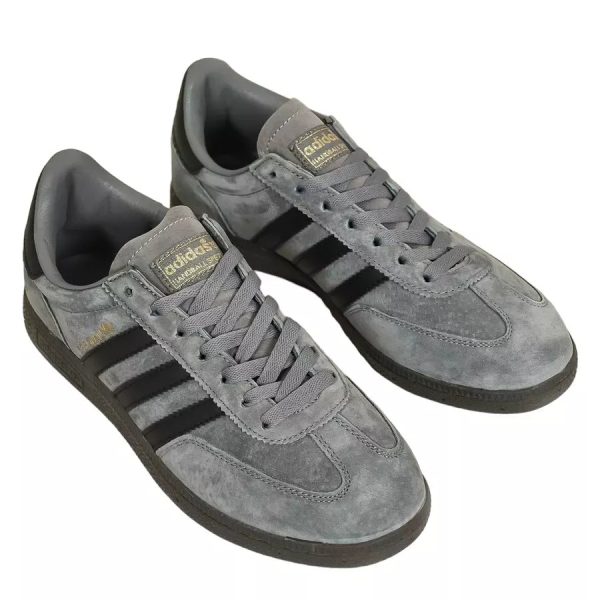Grey suede Adidas sneakers with black stripes and laces tied, angled view outside the shoe.