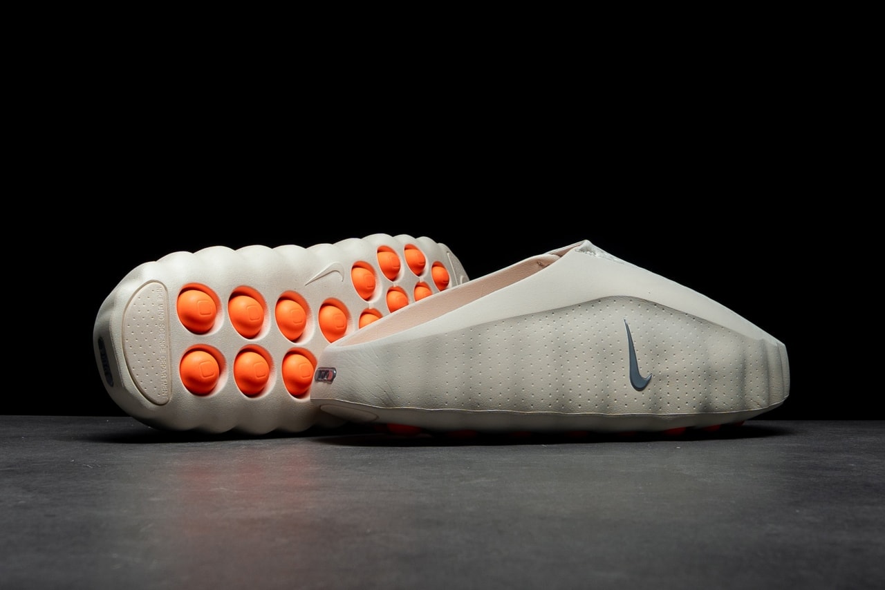 rn-image_picker_lib_temp_487cb993-1700-4fb7-9ef6-c9cdfed9cf56 | UAE SPORT STORE Side view of a white Nike sneaker with a perforated upper, grey swoosh, and bright orange circular outsole pods revealing traction.