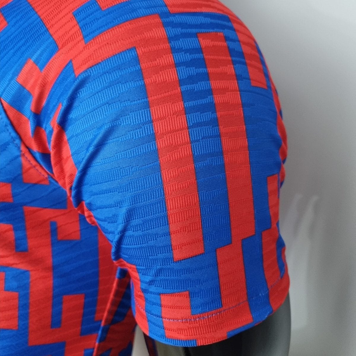 Close-up of blue and red geometric patterned fabric with stitching visible on a garment edge.