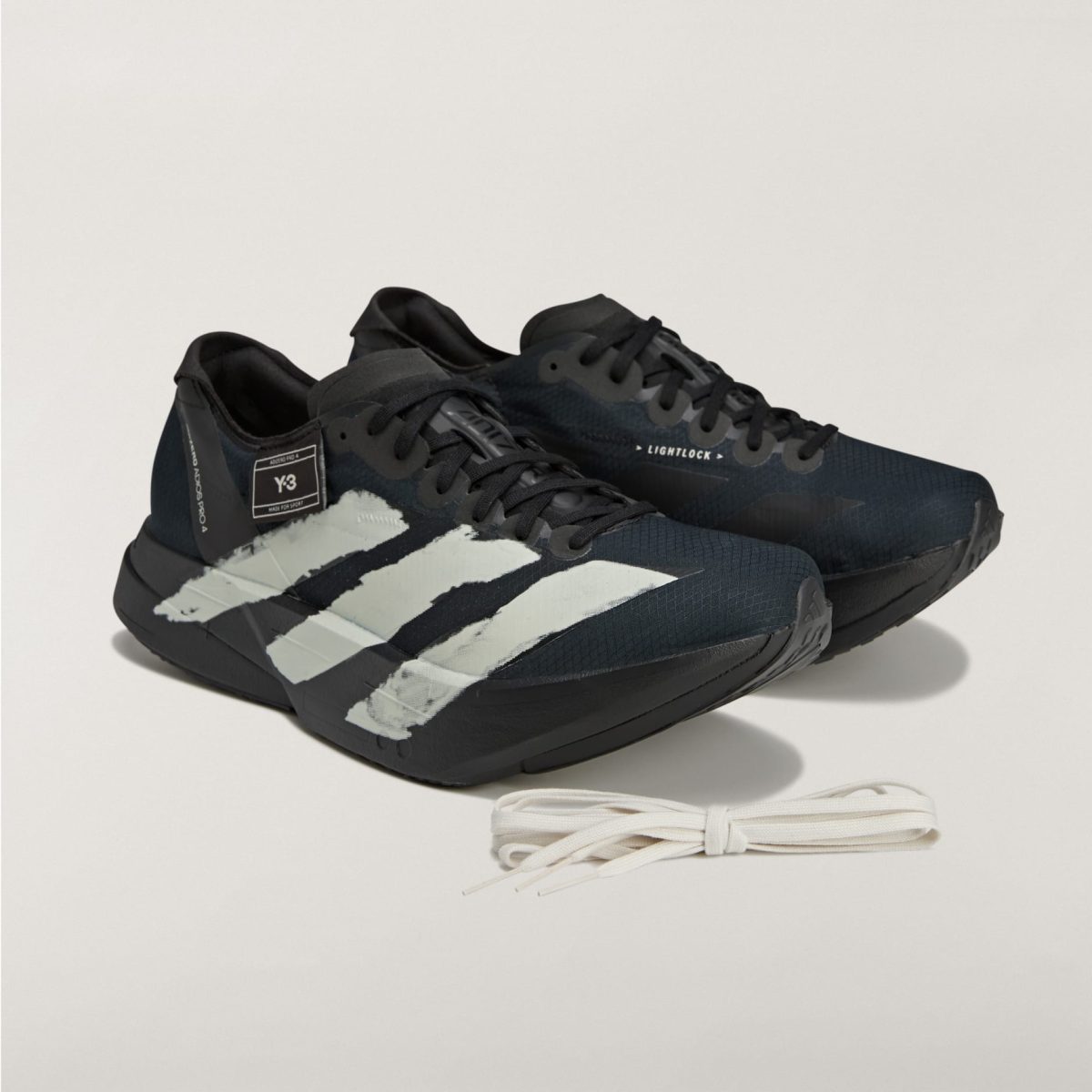 Black Adidas running shoes with white stripes on a light background, white laces nearby.
