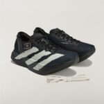 Black Adidas running shoes with white stripes on a light background, white laces nearby.