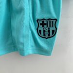 Close-up of a turquoise mesh sports jersey with a partial FC Barcelona crest visible on the right side.