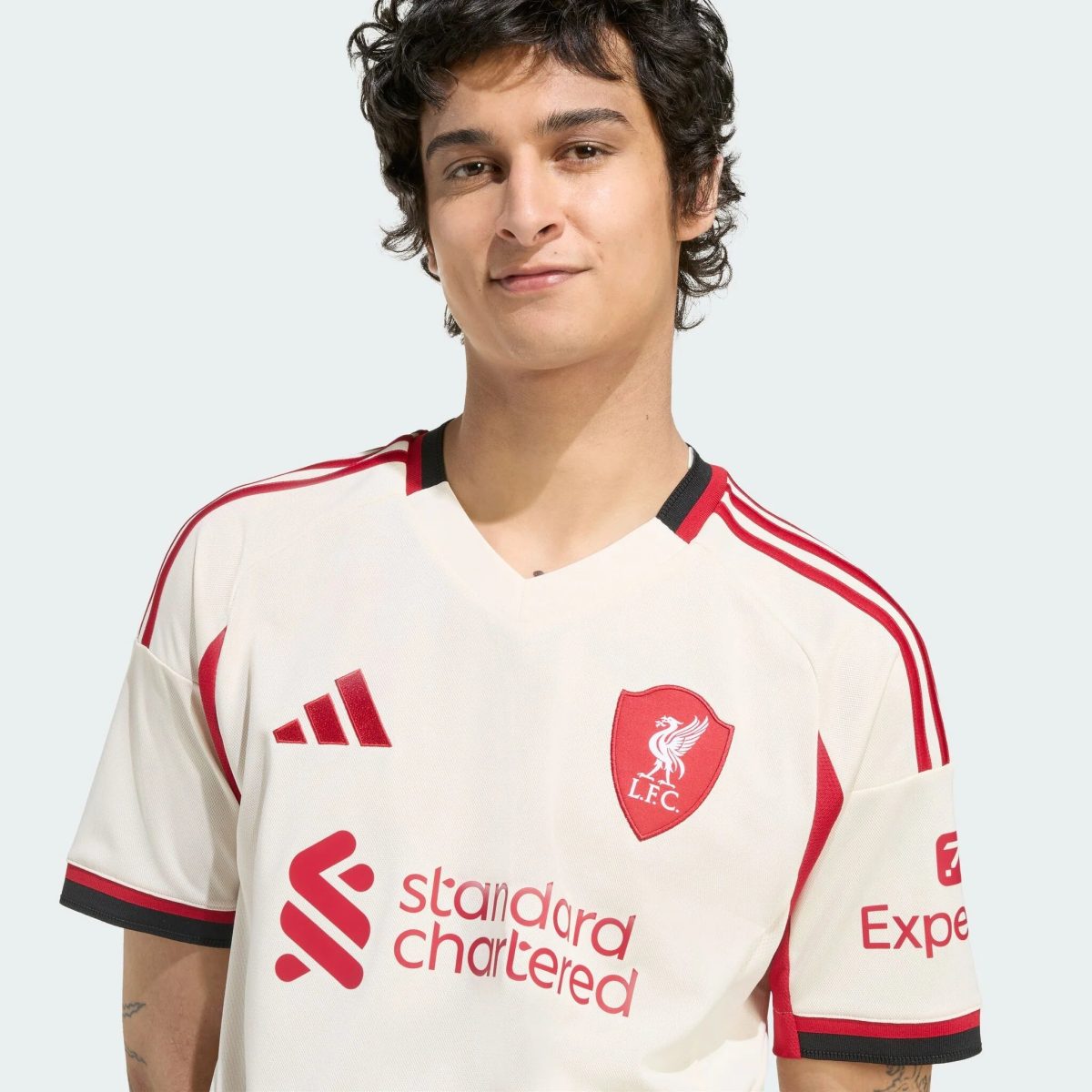 Close-up portrait of a person wearing a white Liverpool FC football jersey with red detailing and crest visible on the chest.