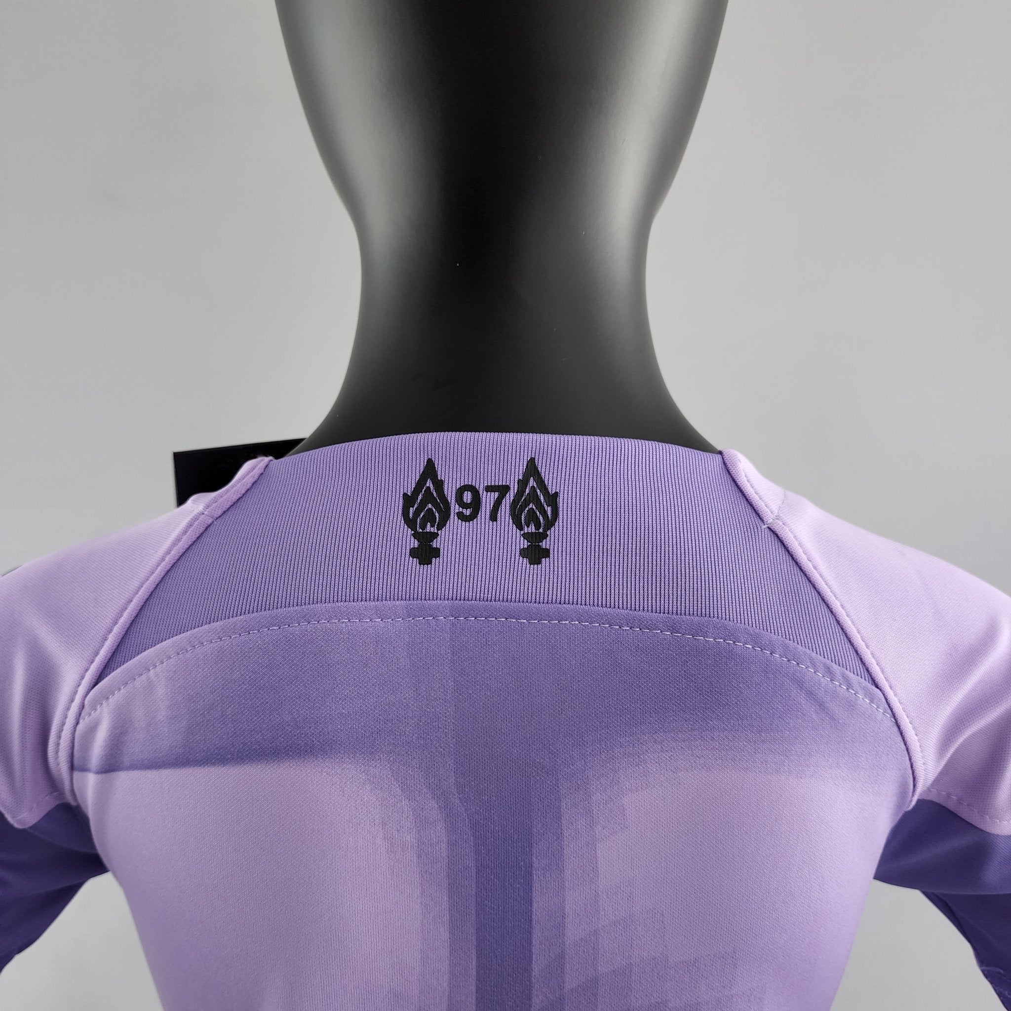 rn-image_picker_lib_temp_4fa8da71-80e9-4919-9860-e3ec7c95e812 | UAE SPORT STORE Back view of a black mannequin wearing a lavender T-shirt with a small black graphic of two pendant-like symbols.