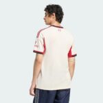Back/side view of a person wearing a white sports jersey with red trim, against a pale blue background.