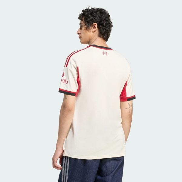 Back/side view of a person wearing a white sports jersey with red trim, against a pale blue background.