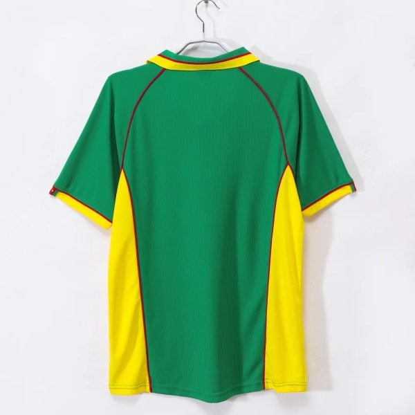 Back view of a green sports jersey with yellow side panels, red piping, and yellow-trimmed sleeves hanging on a hanger.