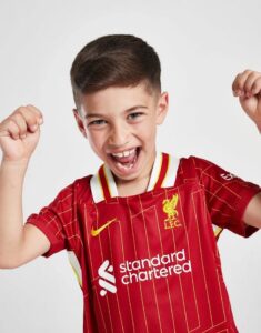 rn-image_picker_lib_temp_588d74c0-7485-4a30-a2ec-293f83d47f35 | UAE SPORT STORE Happy boy wearing a red Liverpool FC jersey, fists raised in celebration.