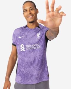 rn-image_picker_lib_temp_5984ad00-a5bf-47f1-a8e2-95ec784e5f3d | UAE SPORT STORE Man in a purple Liverpool FC jersey smiles and reaches his hand toward the camera.