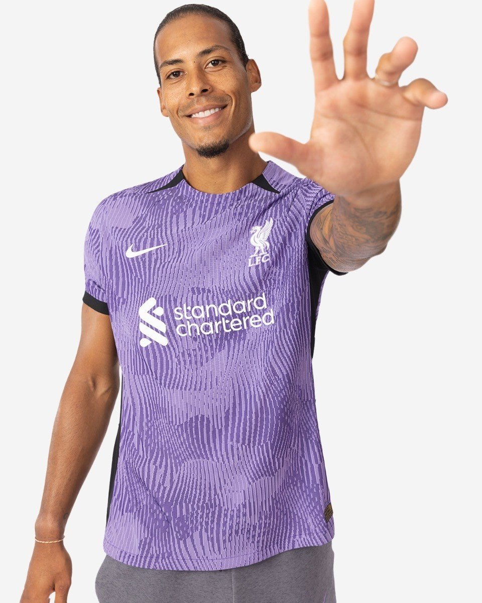 rn-image_picker_lib_temp_5984ad00-a5bf-47f1-a8e2-95ec784e5f3d | UAE SPORT STORE Man in a purple Liverpool FC jersey smiles and reaches his hand toward the camera.