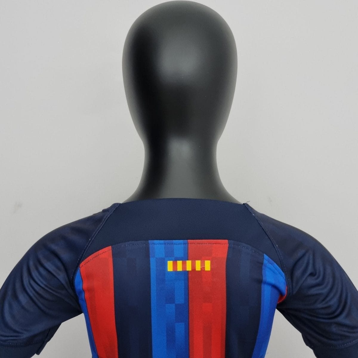 Mannequin torso wearing a navy blue top with bold vertical red and blue stripes and color blocks on the chest area.