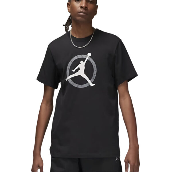 Model wearing a black T-shirt featuring a white Jumpman silhouette inside a gray circular emblem on the chest.