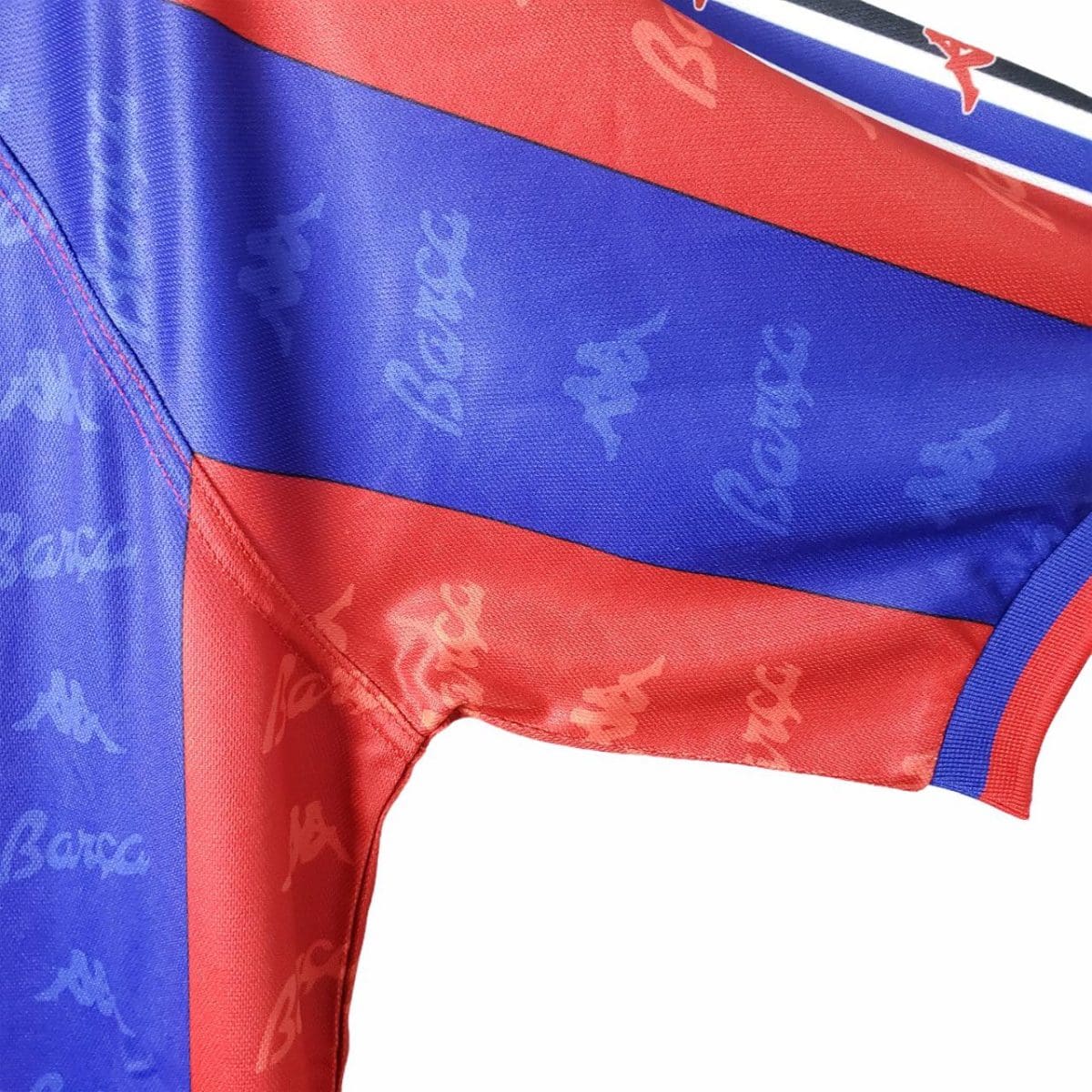 Close-up of a blue and red striped sports jersey fabric with repeating Kappa logos.