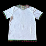 Back view of a white shirt with colorful tribal-inspired embroidery along the collar, sleeve cuffs, and hem.