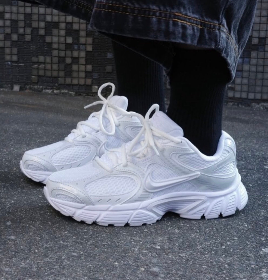 rn-image_picker_lib_temp_67c7307b-d592-4a83-9736-db6d10eaa84d | UAE SPORT STORE White chunky athletic sneakers tied with laces, worn with black socks and denim jeans on a pavement background