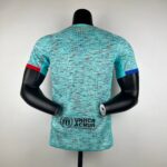 Back view of a turquoise patterned shirt on a mannequin with UNHCR ACNUR text visible at the hem.