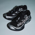 rn-image_picker_lib_temp_6870b7e6-6e26-41bc-b2e1-ad93f01d0929 | UAE SPORT STORE Pair of black and silver running shoes with bold white geometric graphics, resting on a light gray background.