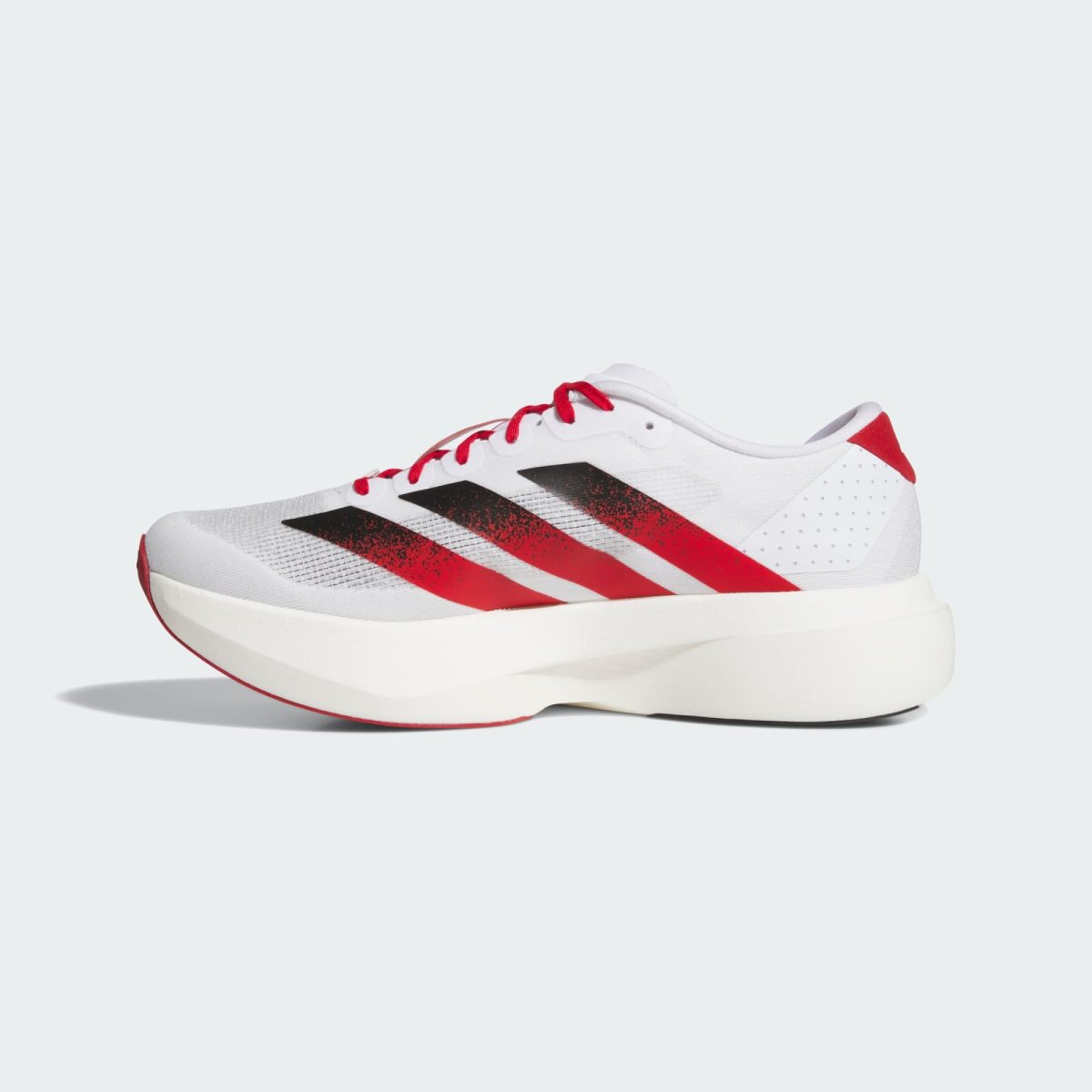 Close-up of a white athletic shoe with red diagonal stripes against a pale background, showing the side panel and laces, bottom edge visible.
