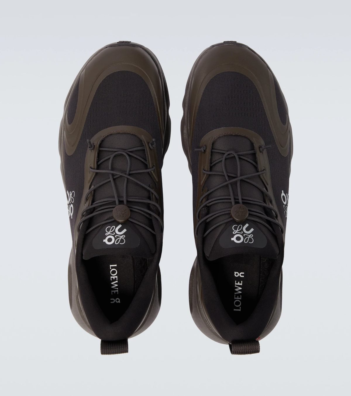 Top-down view of a pair of dark sneakers with brown overlays and laces, photographed from above.