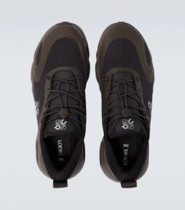 Top-down view of a pair of dark sneakers with brown overlays and laces, photographed from above.