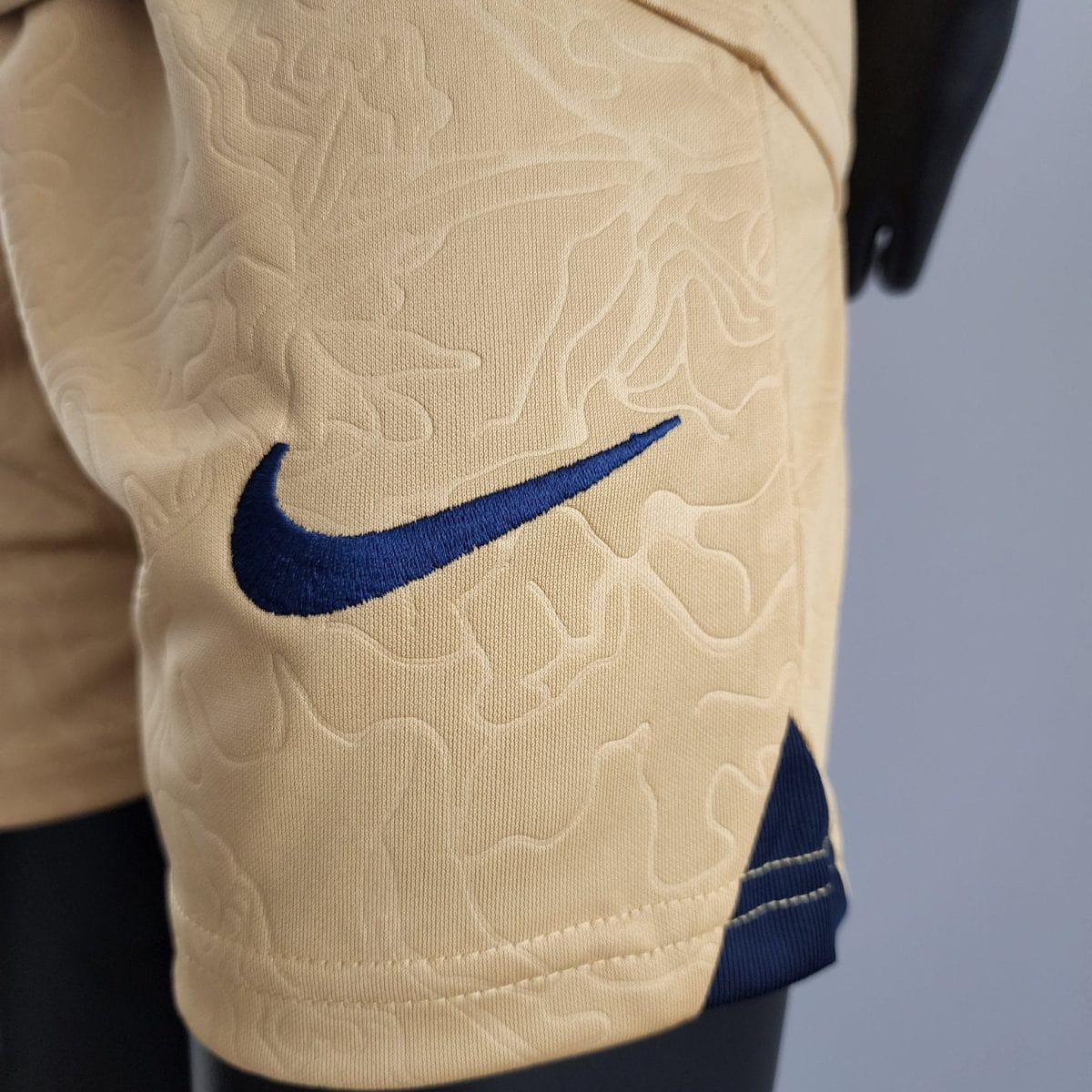 Close-up of beige quilted fabric featuring a blue Nike swoosh logo