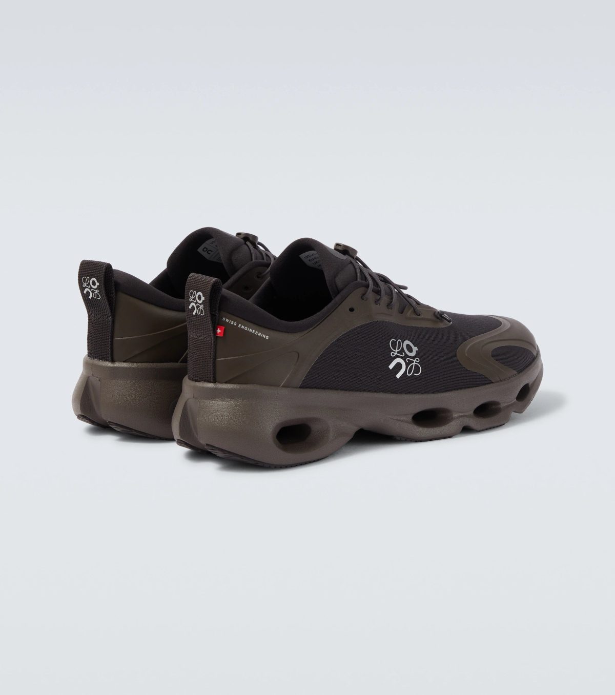 Partial view of brown hiking sneaker showing laces and sole on a pale background.