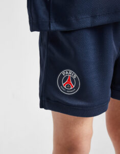 Navy athletic shorts featuring a circular Paris Saint-Germain (PSG) crest on the leg.