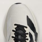 Close-up of a light gray sneaker toe with black laces and textured fabric.