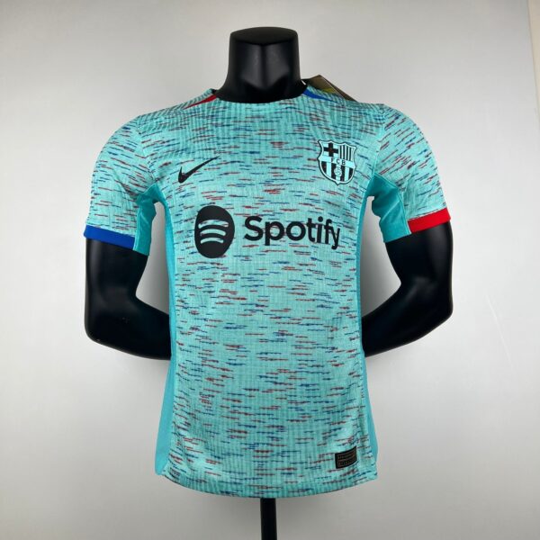 Mannequin wearing a turquoise Barça football jersey with a black Spotify logo across the chest and the FC Barcelona crest on the left breast area, posed against a plain background.