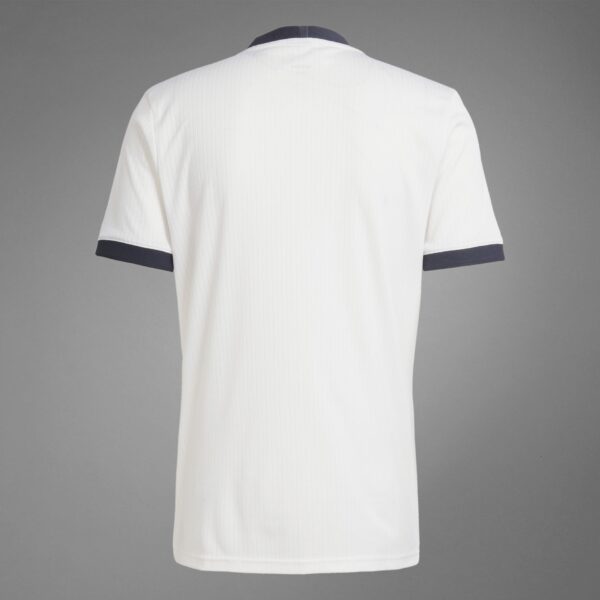 Back view of a white pinstriped polo shirt with navy sleeve trim against a gray background.