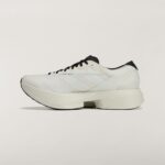 White athletic sneaker with black laces, shown in a side profile against a light background; features a textured sole and black heel detail.