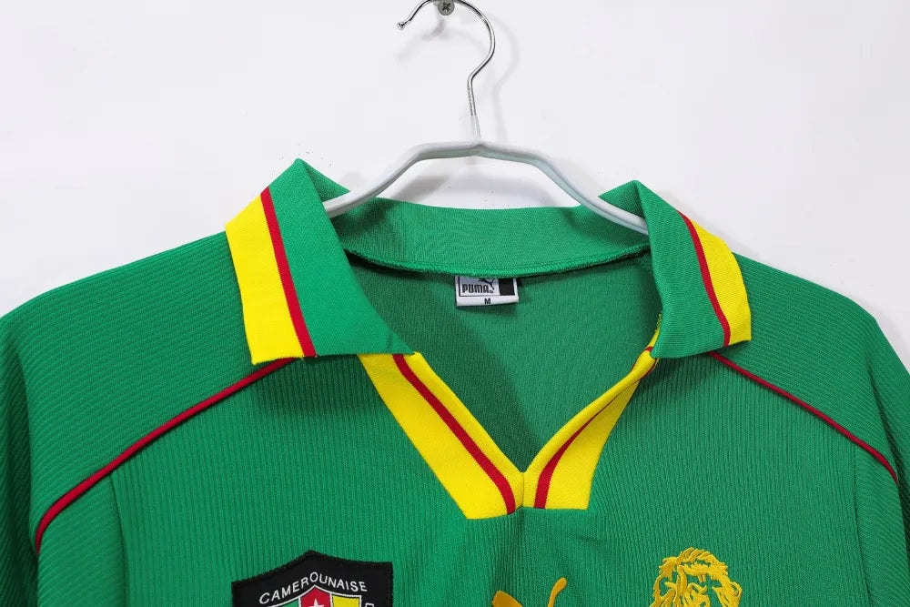 rn-image_picker_lib_temp_967f3c4a-b9e4-47cd-87a7-6c1672248d33 | UAE SPORT STORE Green sports jersey with yellow and red trim on the collar, hanging on a hanger on a white background.
