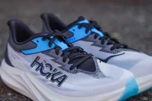 rn-image_picker_lib_temp_9c100461-bb9f-4058-8875-4e1a49360503 | UAE SPORT STORE Pair of white, gray, and blue HOKA running shoes with black laces on a dark pavement surface.