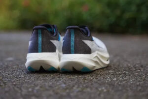rn-image_picker_lib_temp_9e838319-3adf-4df5-88ad-7af24356b93c | UAE SPORT STORE Rear view of two gray running shoes with teal accents on a paved path.