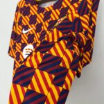 Close-up of a garment featuring a bold red, yellow, and navy diamond pattern with a white Nike swoosh visible on the fabric edge.