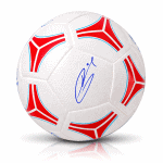 Autographed white soccer ball with red and blue geometric panels on a plain background.