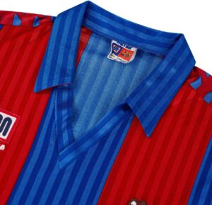 rn-image_picker_lib_temp_a648a122-ffa6-4b28-8133-44444d1a5083 | UAE SPORT STORE Close-up of a red and blue striped collared shirt with a small FC Barcelona label near the collar