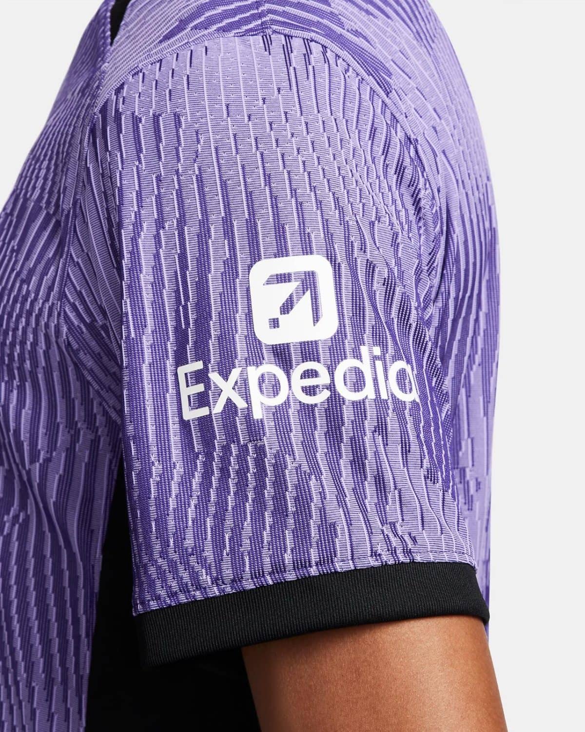 Close-up of a purple geometric-patterned sports jersey sleeve with a white Expedia logo and black cuff.