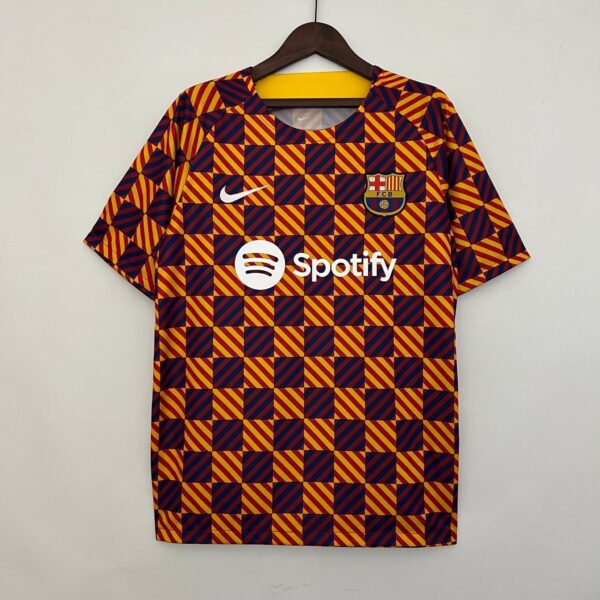 FC Barcelona football jersey on a hanger, featuring a red and yellow diagonal-square pattern with the club crest and white Nike swoosh.