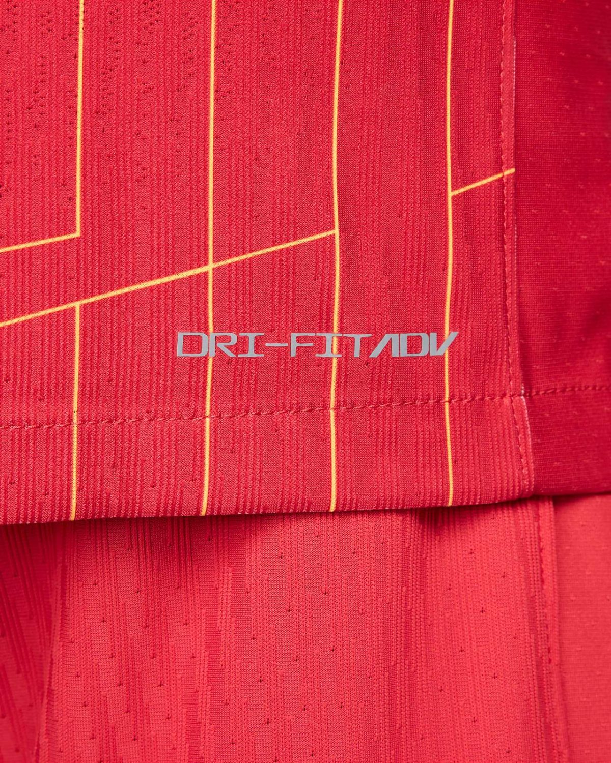 Close-up of red athletic fabric with vertical yellow piping and the DRI-FIT ADV logo visible.