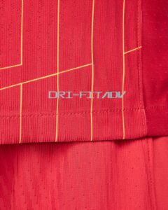 Close-up of red athletic fabric with vertical yellow piping and the DRI-FIT ADV logo visible.