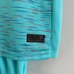 Close-up of turquoise fabric with red and blue streaks and a black label that reads 'Engineered'.
