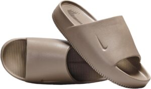 Brown Nike slide sandals with textured footbeds and ribbed outsole, viewed from side.