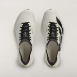 Top-down view of a pair of white sneakers with black laces on a light background, side by side.