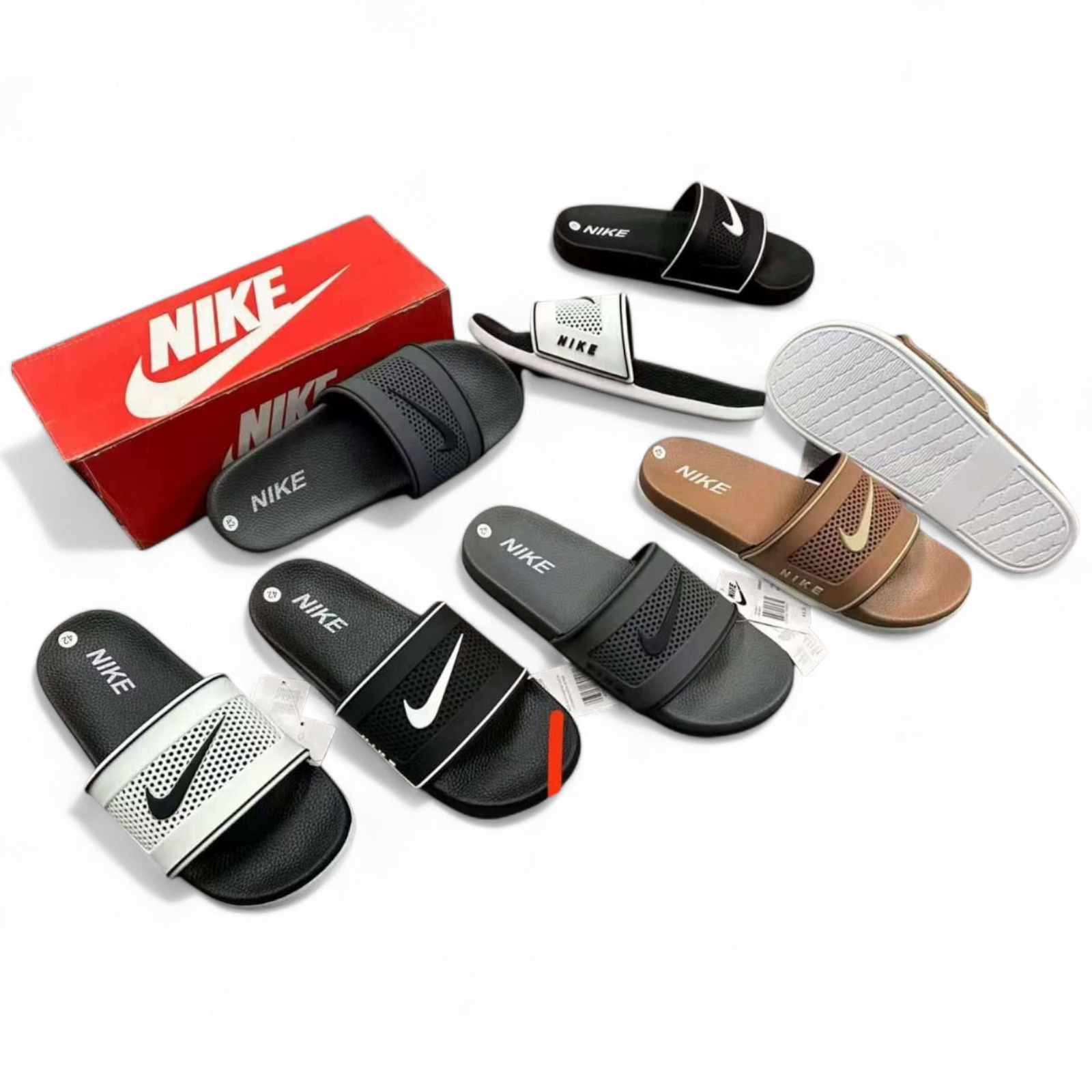 rn-image_picker_lib_temp_b6da2401-ea16-4420-8176-adafd13cc1a1 Assortment of Nike slide sandals in black, white, and beige with a red Nike box in the background