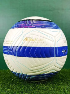 Soccer ball with white and blue panel pattern on grass, labeled Nike Aerow Sculpt Technology.