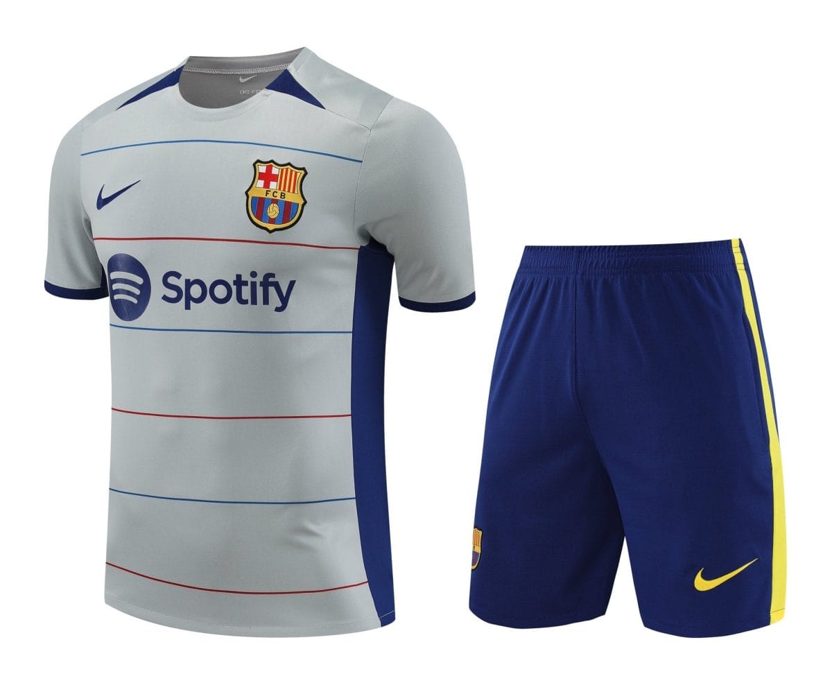 Barça football jersey with light gray body, blue trim, crest, Nike swoosh, and Spotify sponsor logo, paired with blue shorts featuring a yellow stripe.