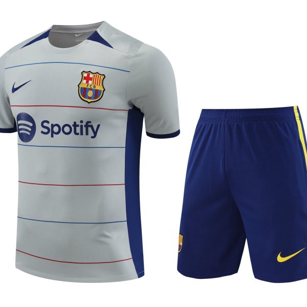 Barça football jersey with light gray body, blue trim, crest, Nike swoosh, and Spotify sponsor logo, paired with blue shorts featuring a yellow stripe.