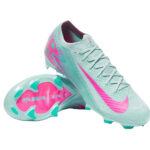 Mint green soccer cleat with pink Nike swoosh and teal accents, studded outsole visible from side view of two shoes