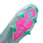 Bottom of a turquoise soccer cleat with pink sole and turquoise studs on a white background